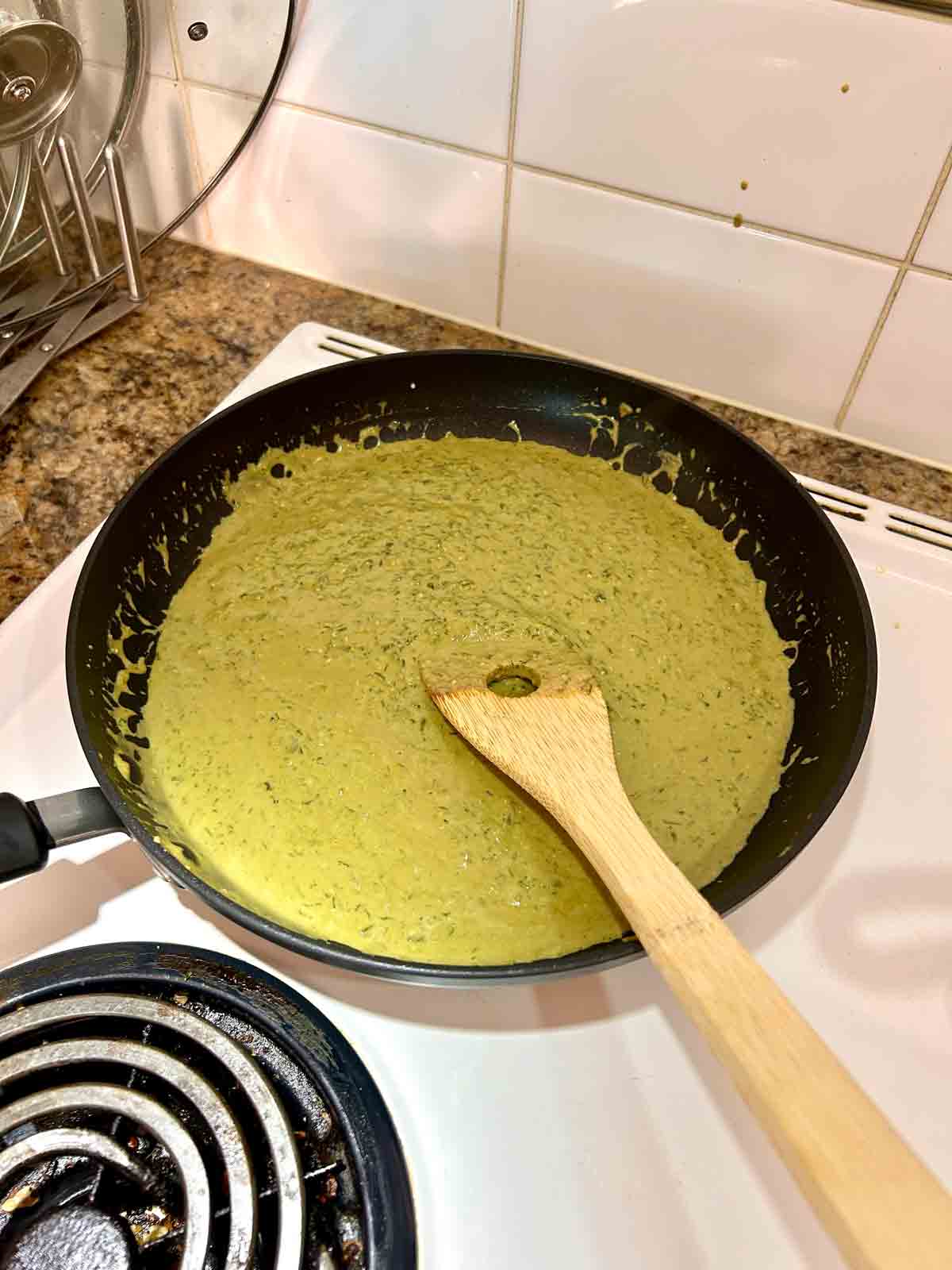 pesto cream sauce simmering in pan.