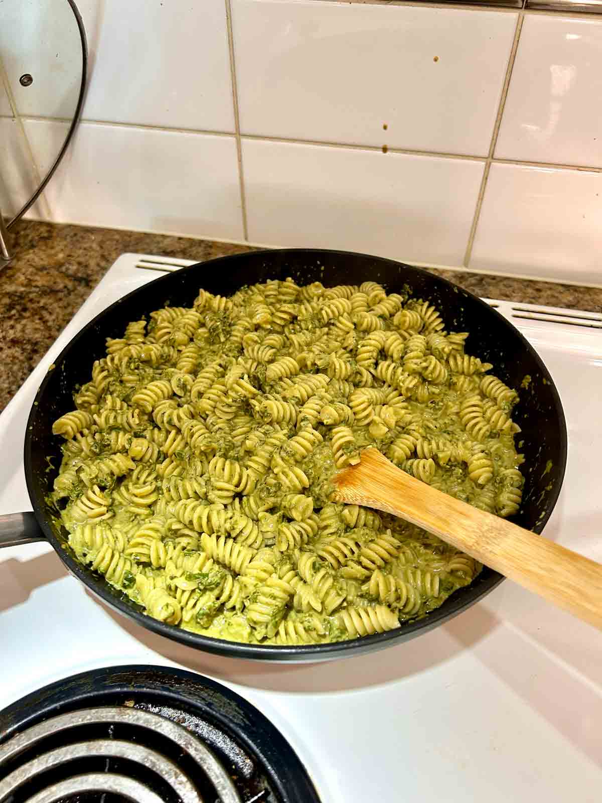 rotini tossed with cream sauce in pan.