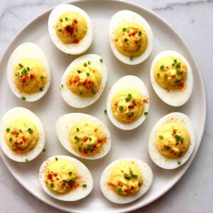 plate of deviled eggs with paprika and chopped chives.