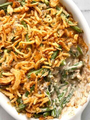 close up of green bean casserole with portion of it scooped out of baking dish.