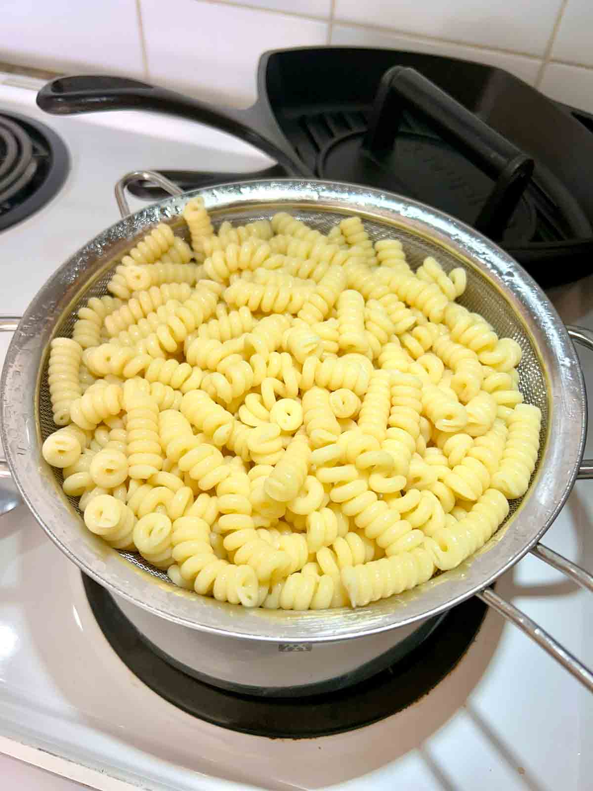 cooked fusilli draining over pot.