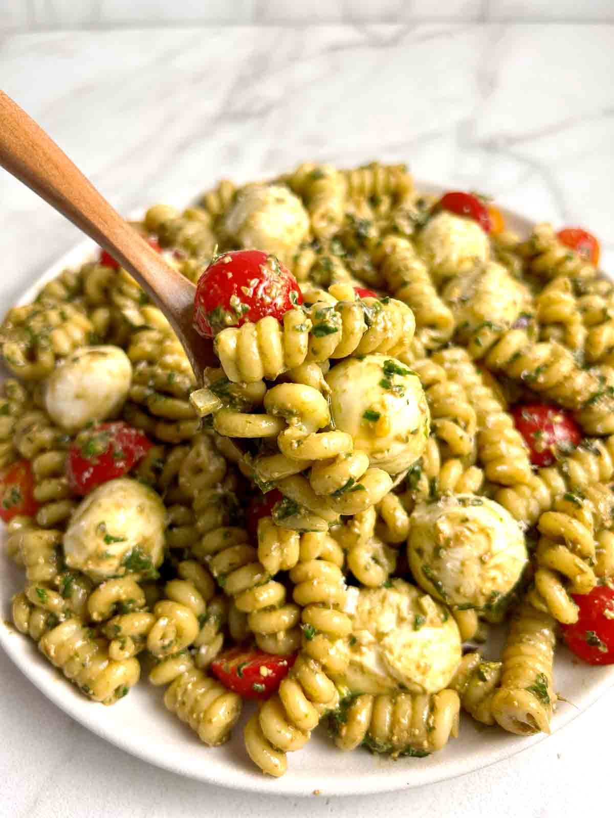 spoon lifting pesto pasta salad.