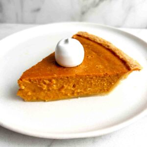 slice of pumpkin pie with cream on top.