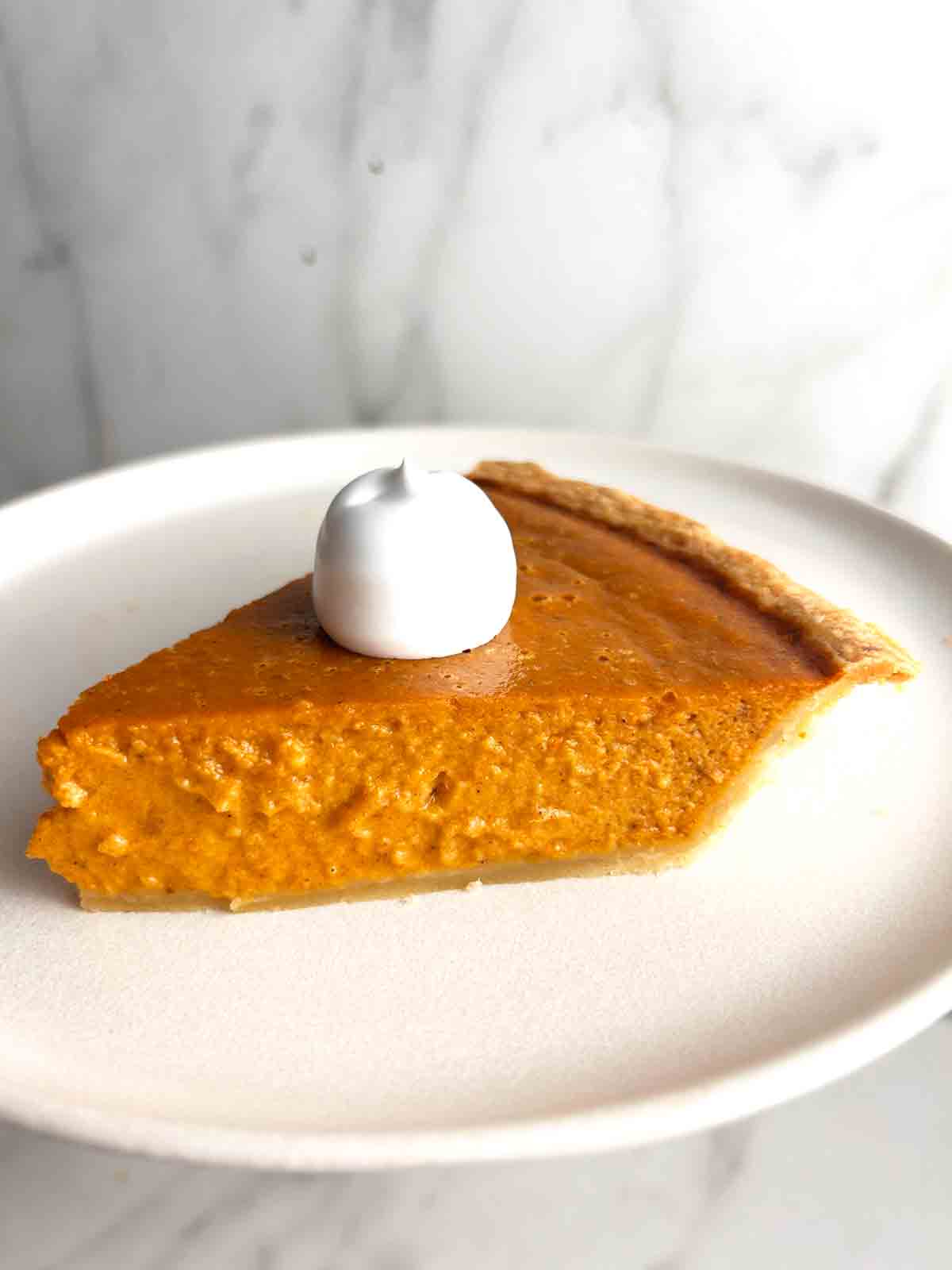 slice of pumpkin pie with cream on top.