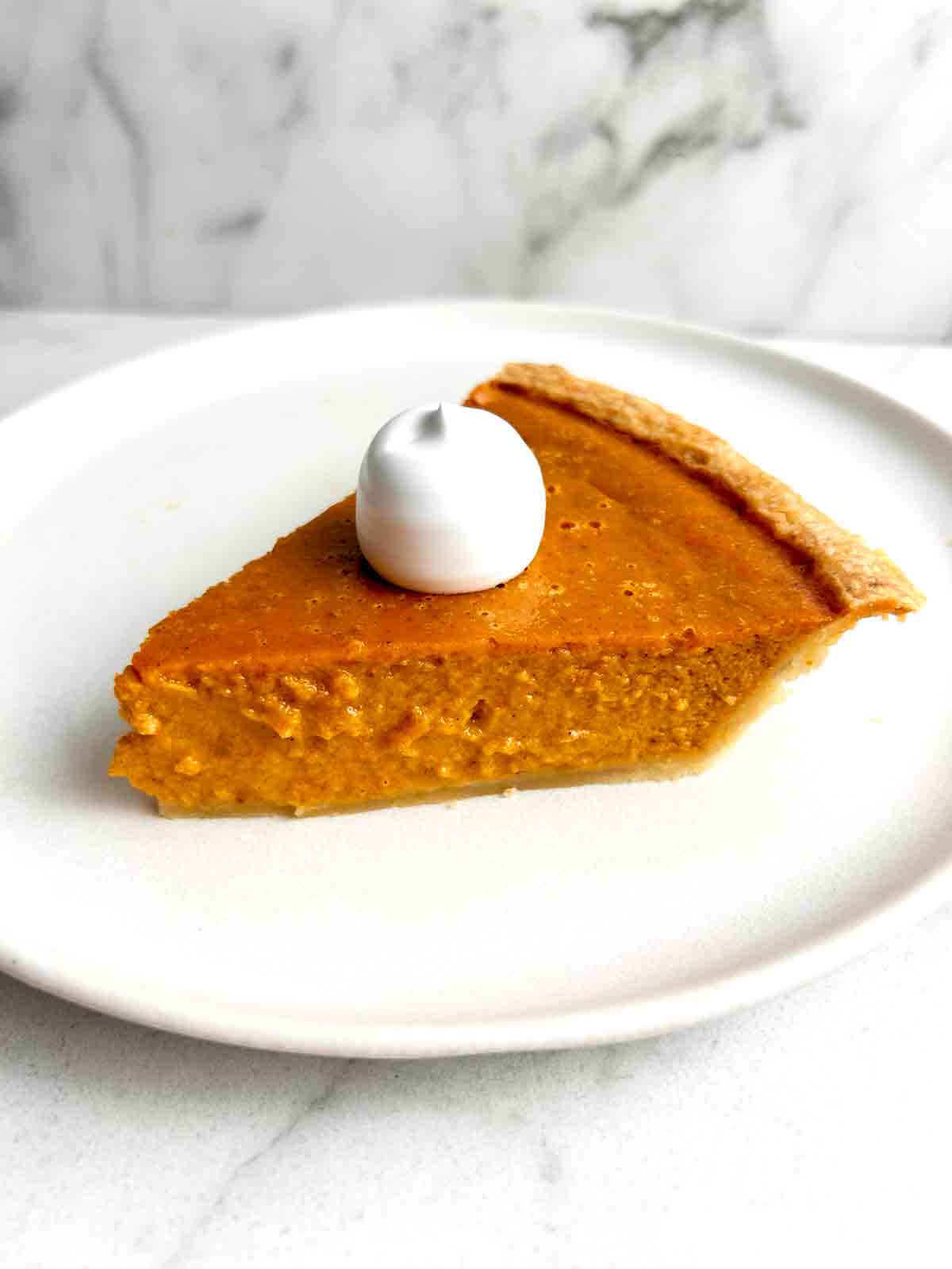 slice of pumpkin pie with cream on top.