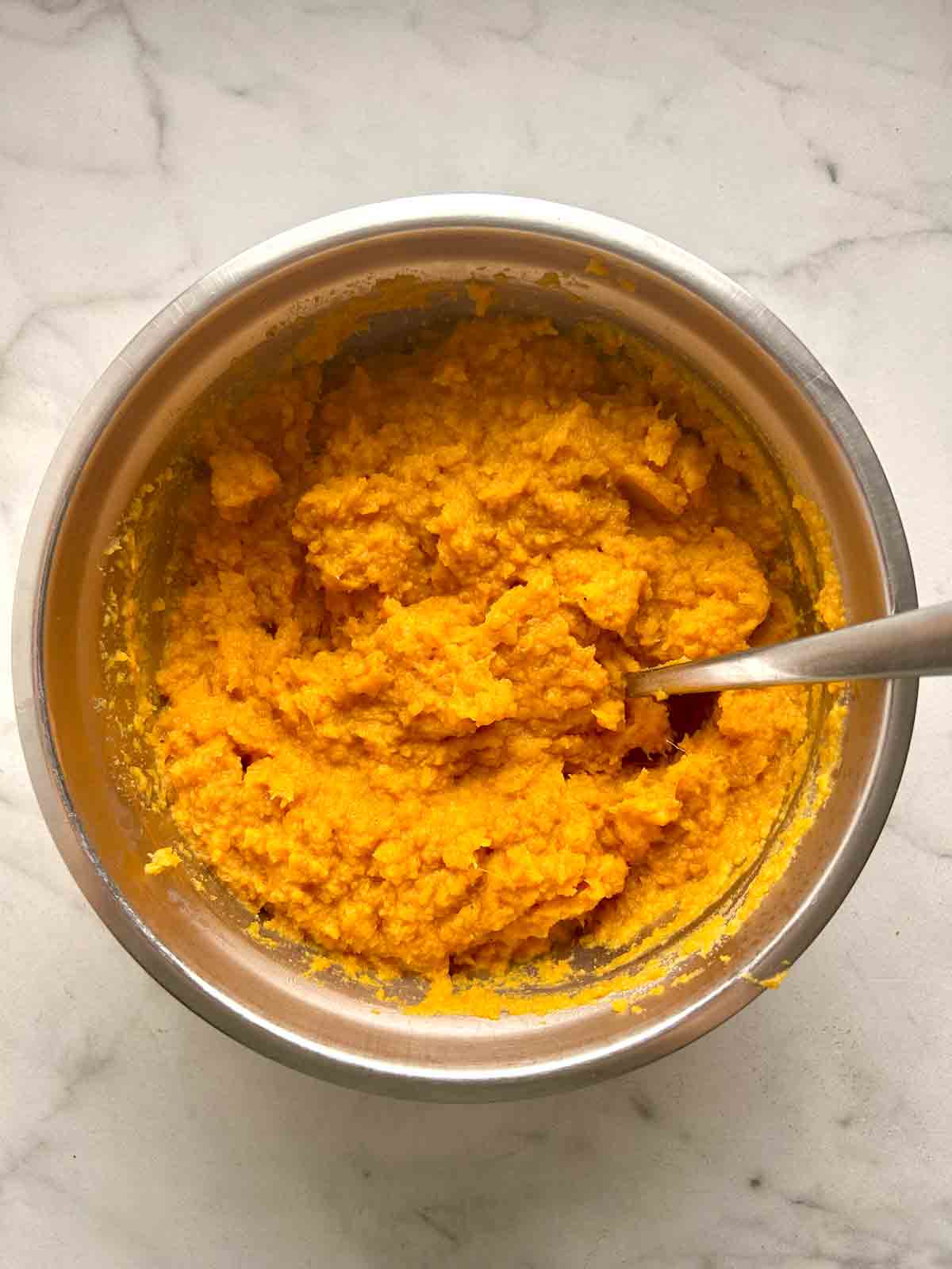 sweet potatoes being mashed with other ingredients in bowl.