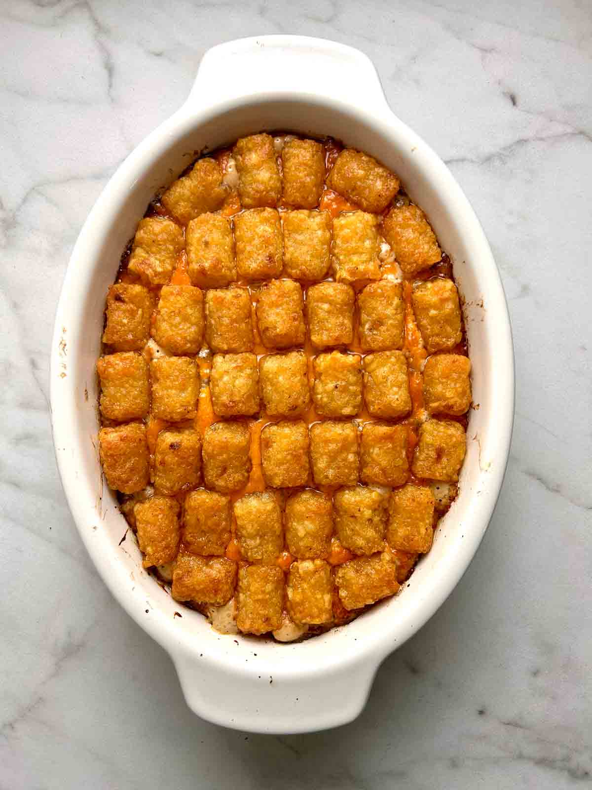 tater tot casserole after baking; tots are golden brown and filling is bubbling up.