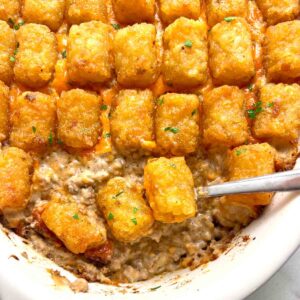 close up of tater tot casserole with spoon scooping some of it out.