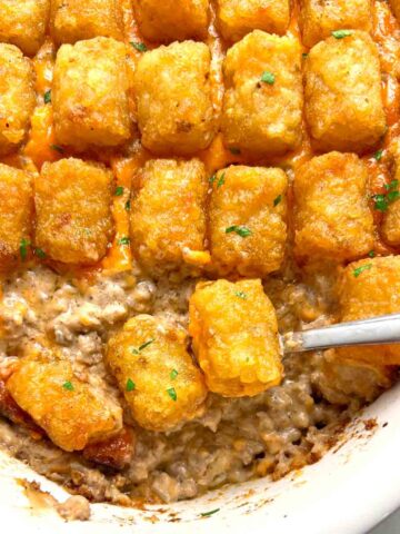 close up of tater tot casserole with spoon scooping some of it out.