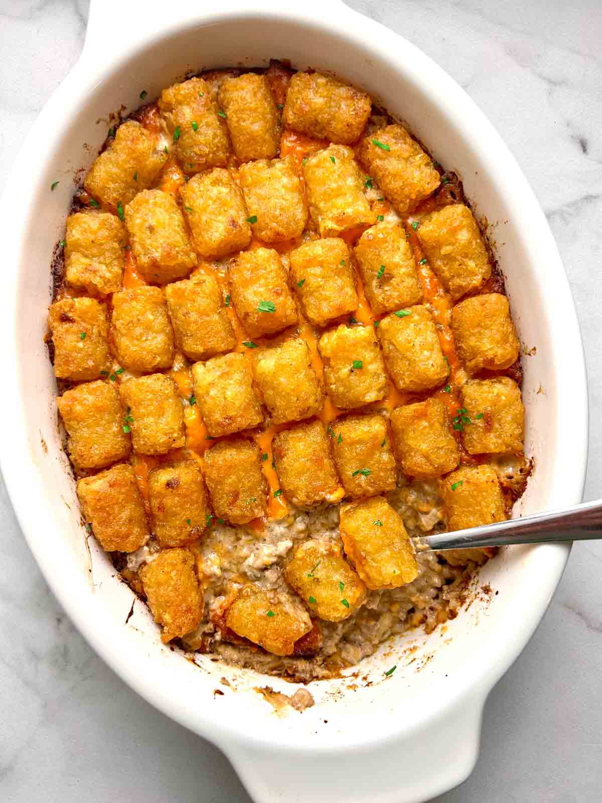 overhead shot of tater tot casserole with spoon scooping some of it out.
