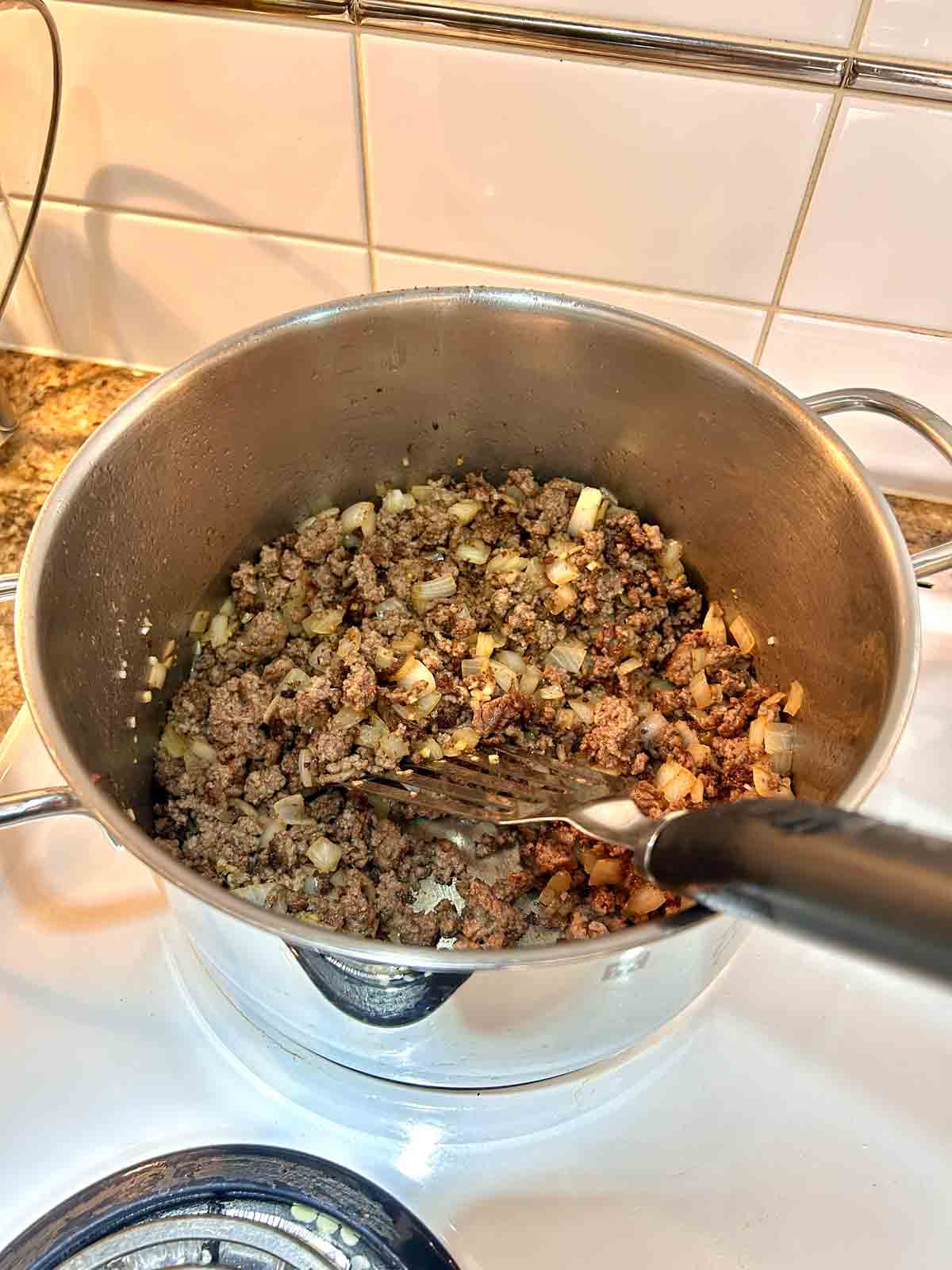 ground beef, onions, and garlic cooked in pot.