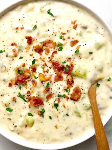 bowl of clam chowder with crispy bacon and parsley sprinkled on top.