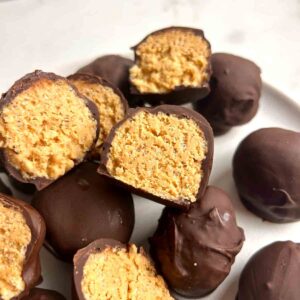 plate of peanut butter balls with some split in half to show inside.