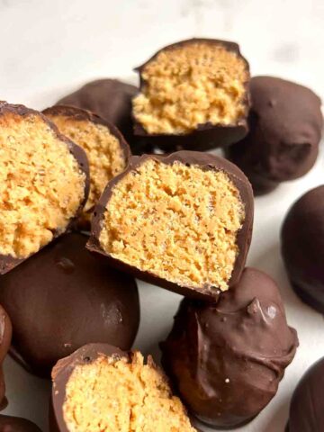 plate of peanut butter balls with some split in half to show inside.