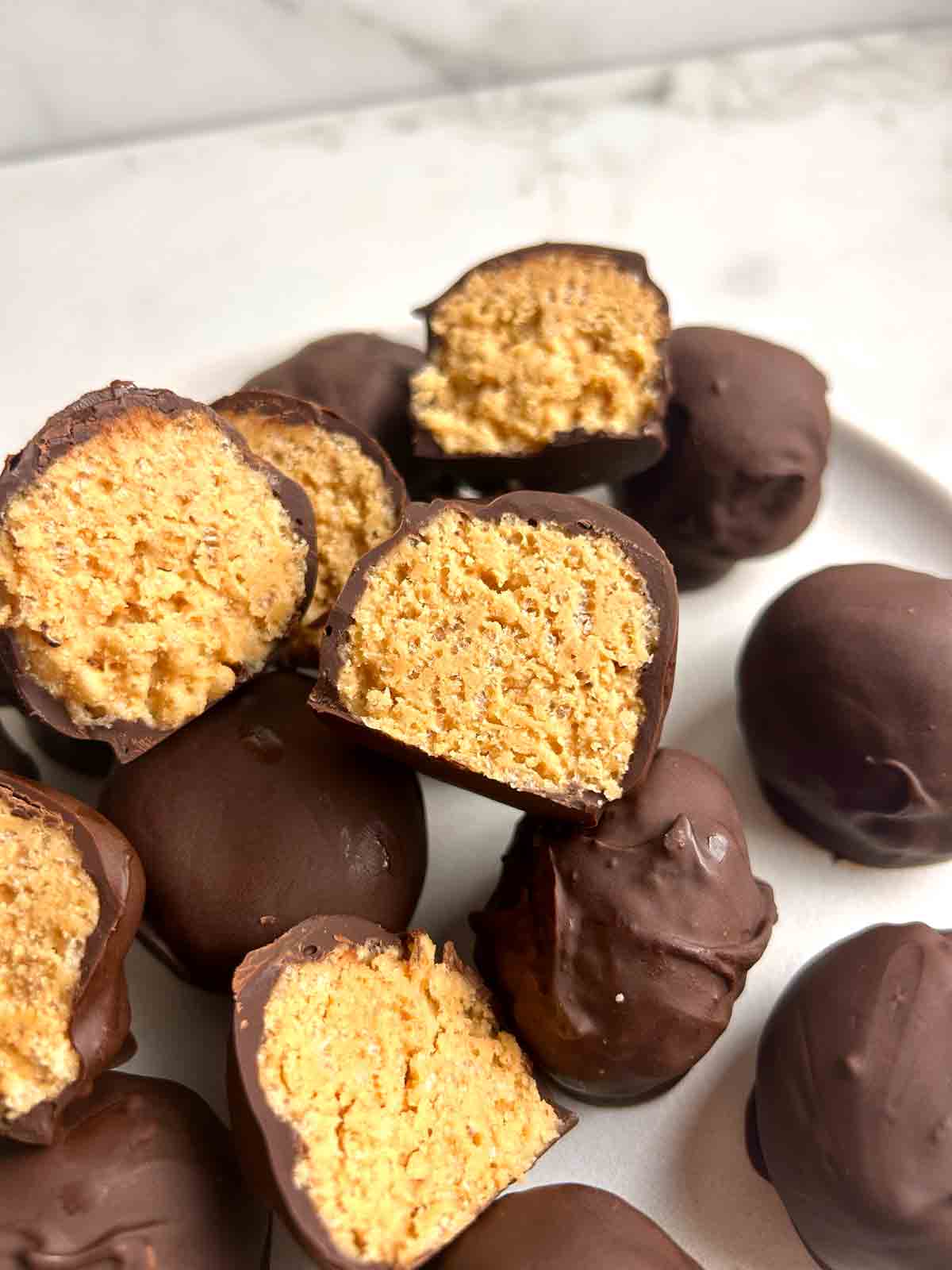 plate of peanut butter balls with some split in half to show inside.