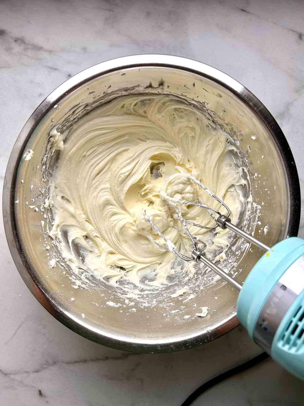 cream cheese and powdered sugar being beaten until smooth.