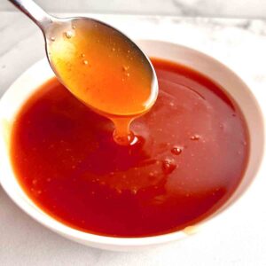 spoon lifting sweet and sour sauce from bowl.