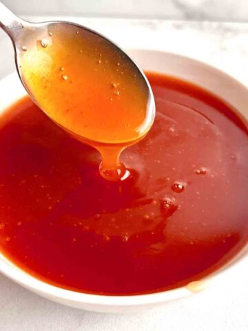 spoon lifting sweet and sour sauce from bowl.