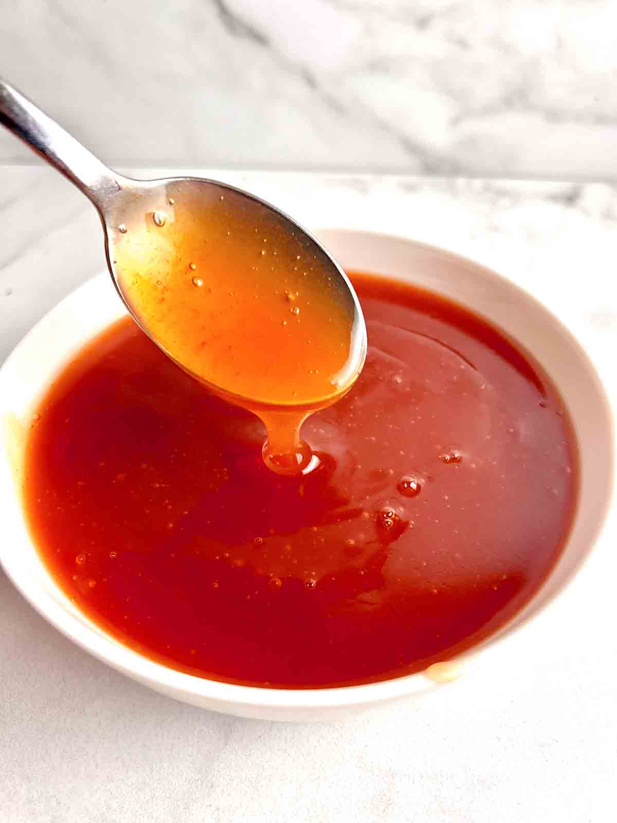 spoon lifting sweet and sour sauce from bowl.