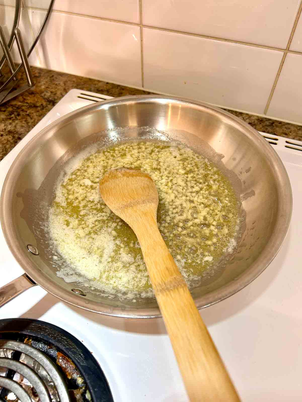 garlic being cooked in butter in skillet.