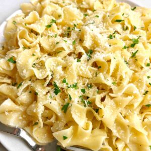 close up of buttered noodles with extra Parmesan sprinkled on top.