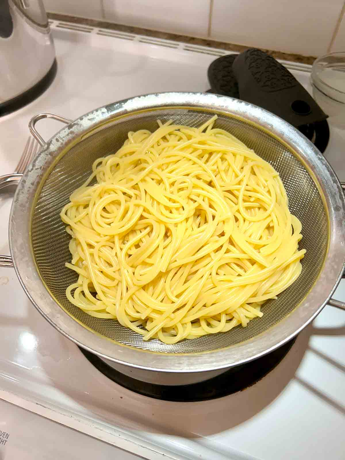 cooked spaghetti draining in colander.