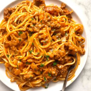 plate of cheesy taco spaghetti garnished with parsley.