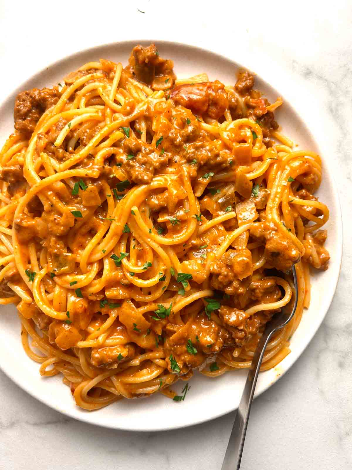 plate of cheesy taco spaghetti garnished with parsley.