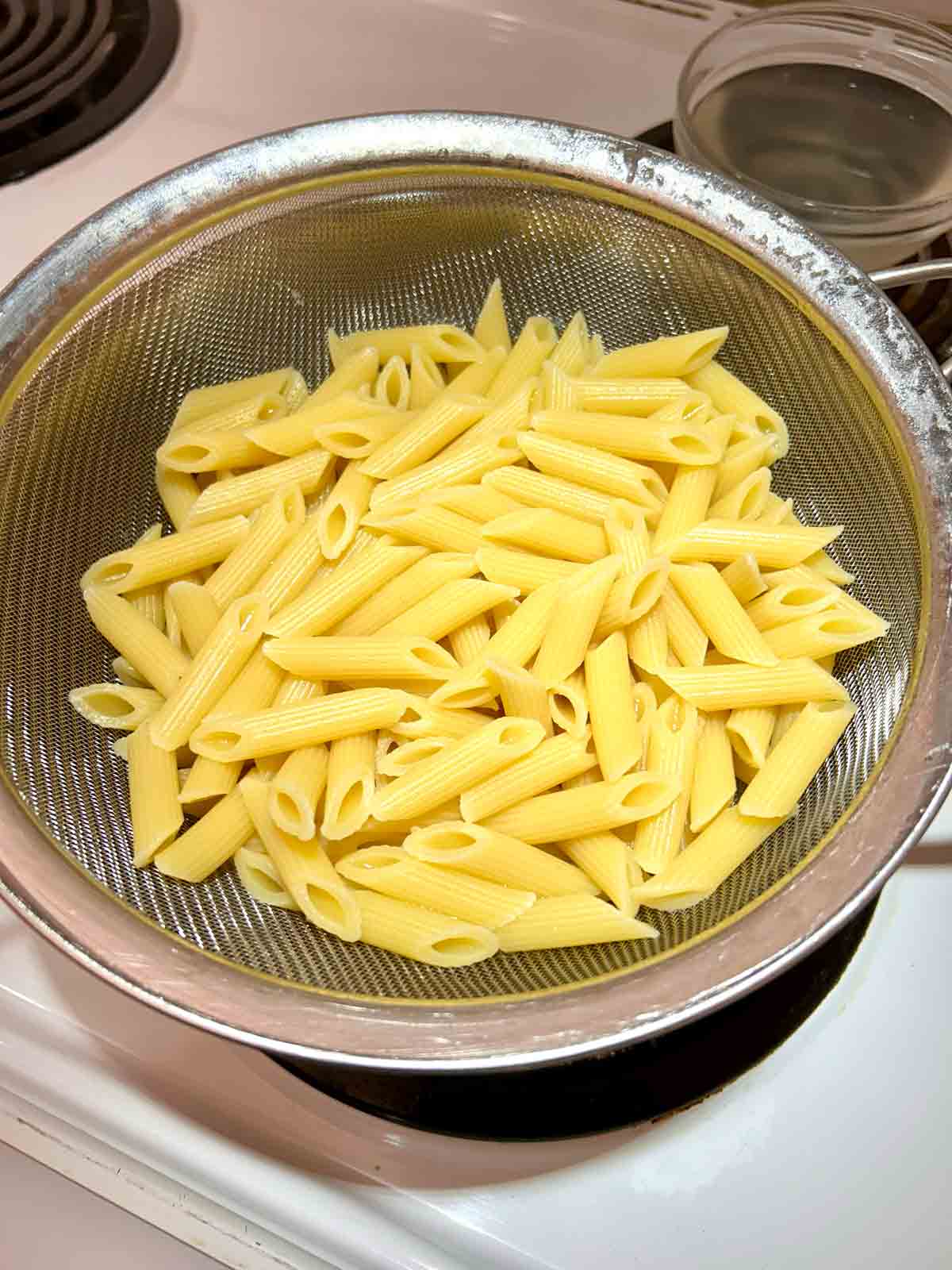 cooked pasta draining in strainer.
