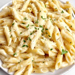 close up of creamy garlic pasta with chopped parsley garnish.