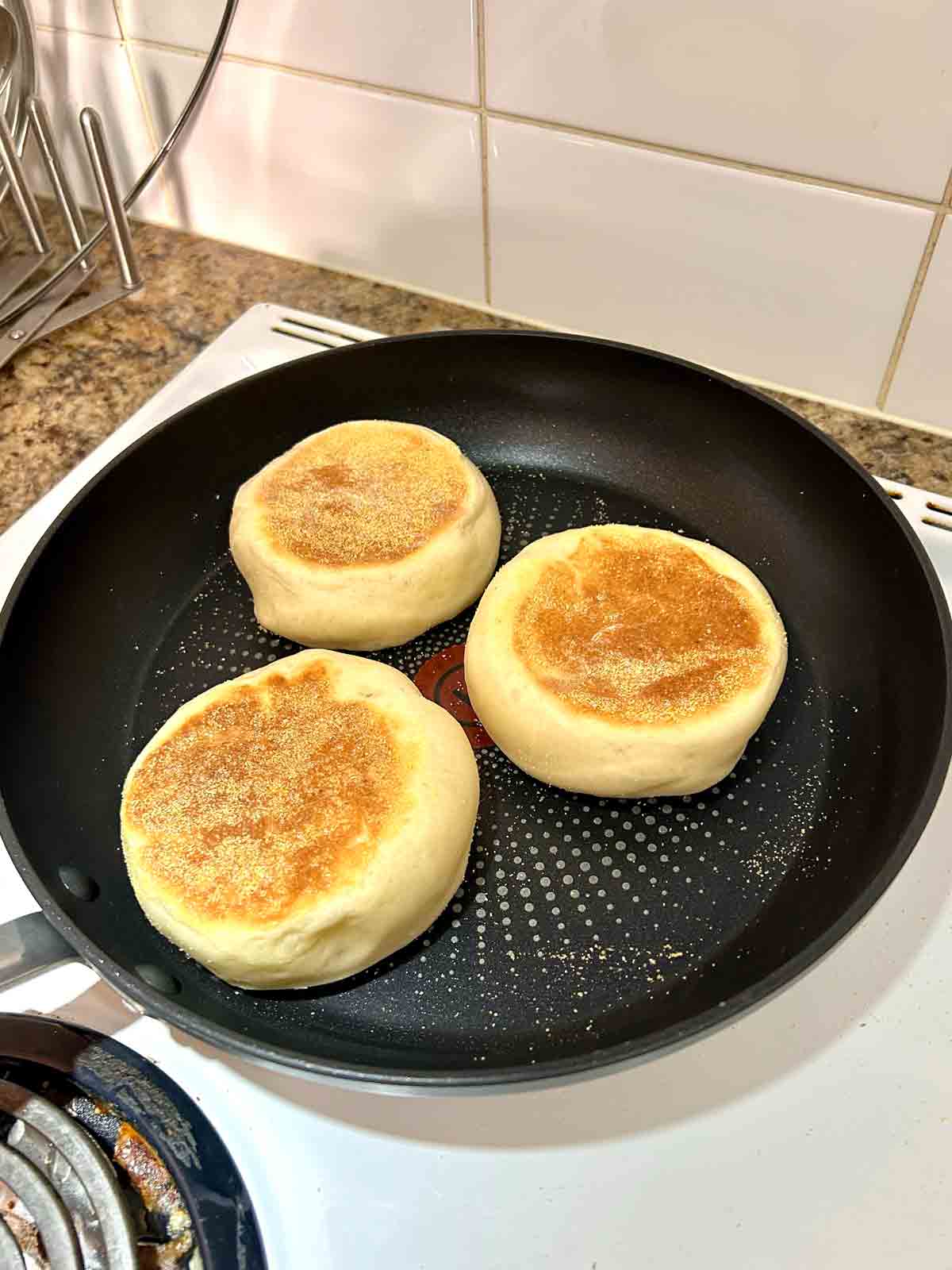English muffins flipped to show golden brown side in skillet.