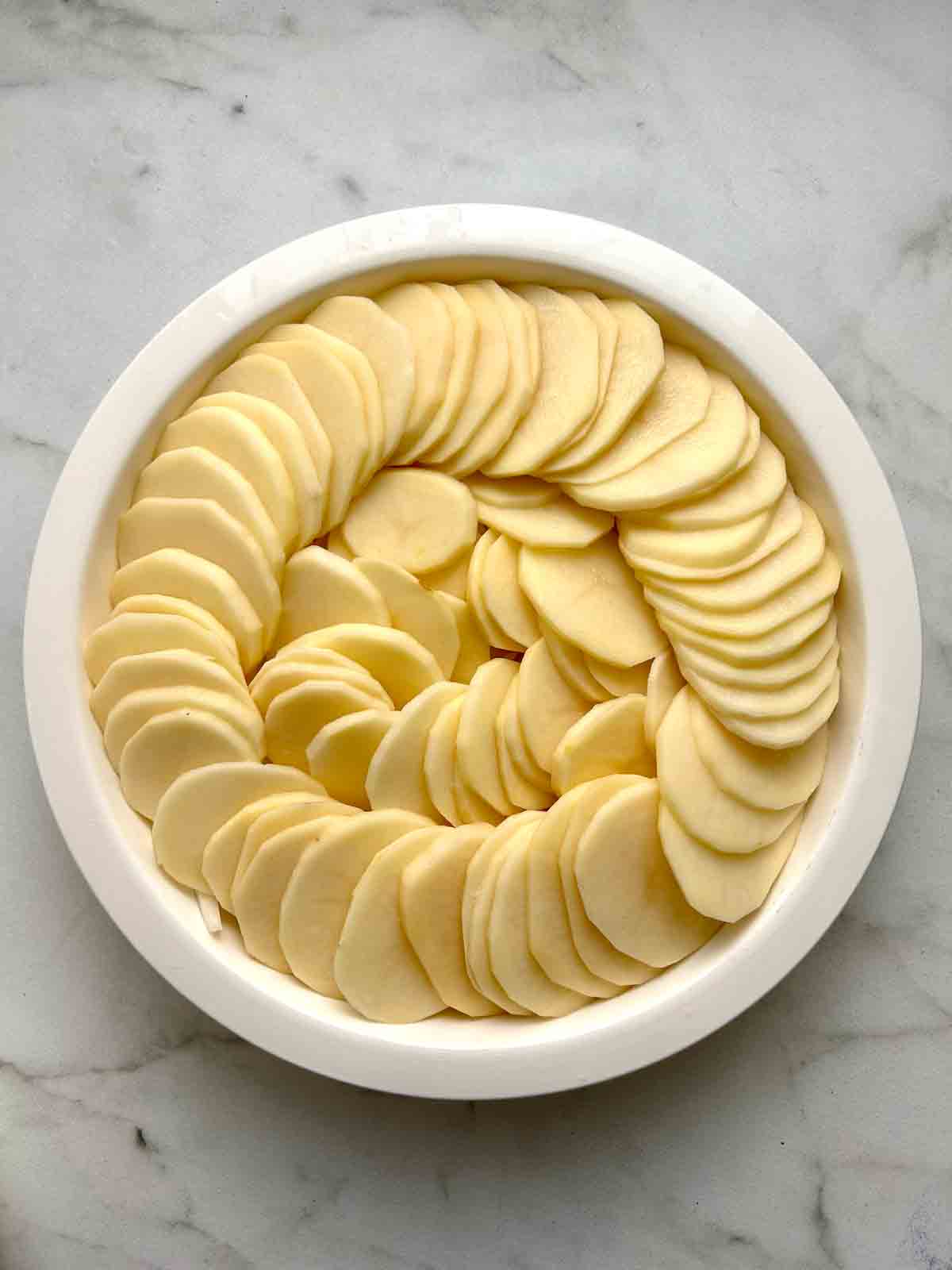 sliced potatoes layered in baking dish.