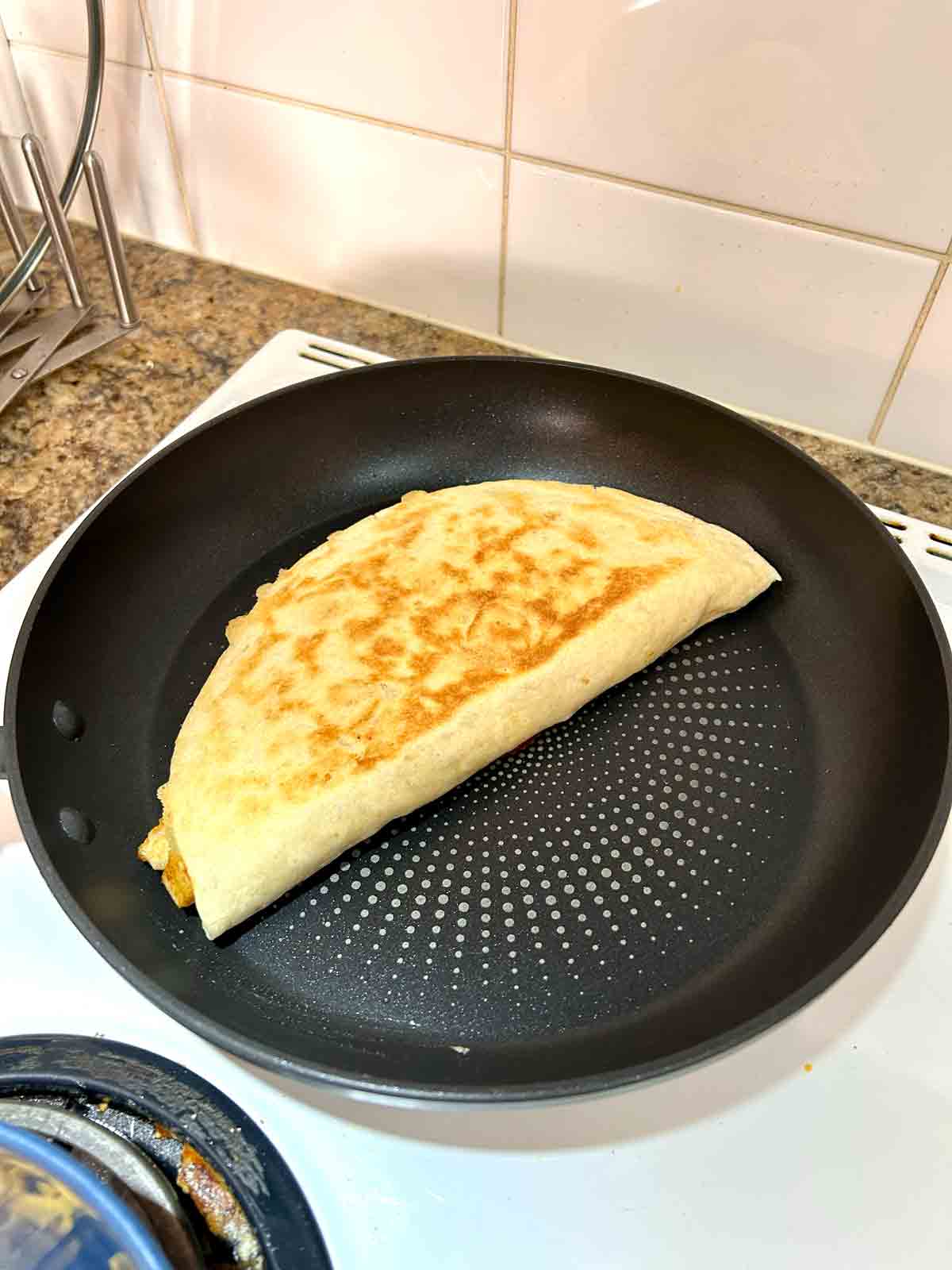 quesadilla being cooked in pan.