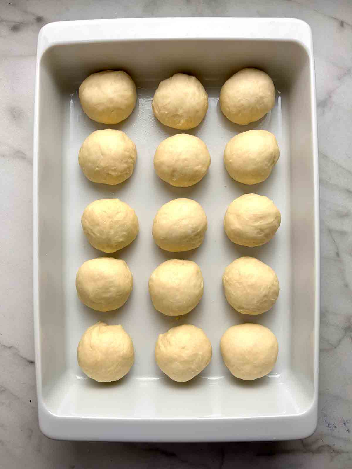 dough shaped into balls and arranged in baking dish.