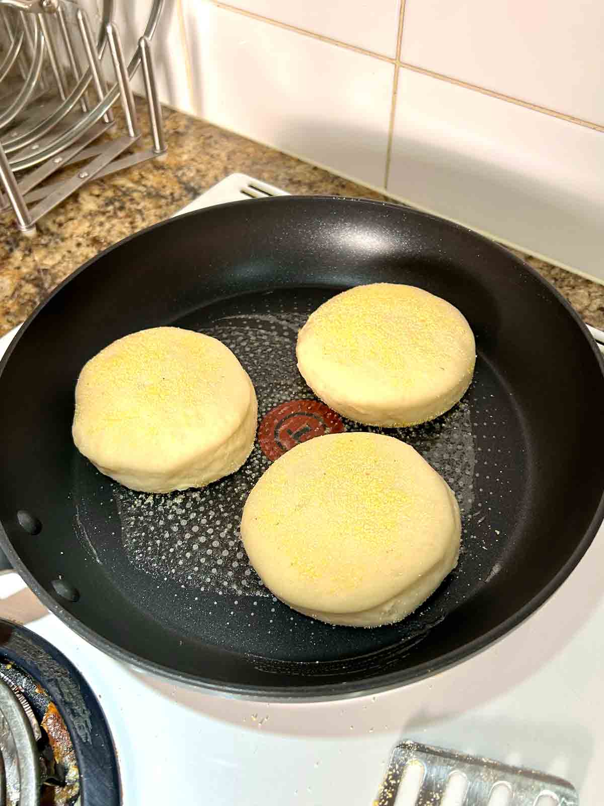 English muffins cooking in skillet.