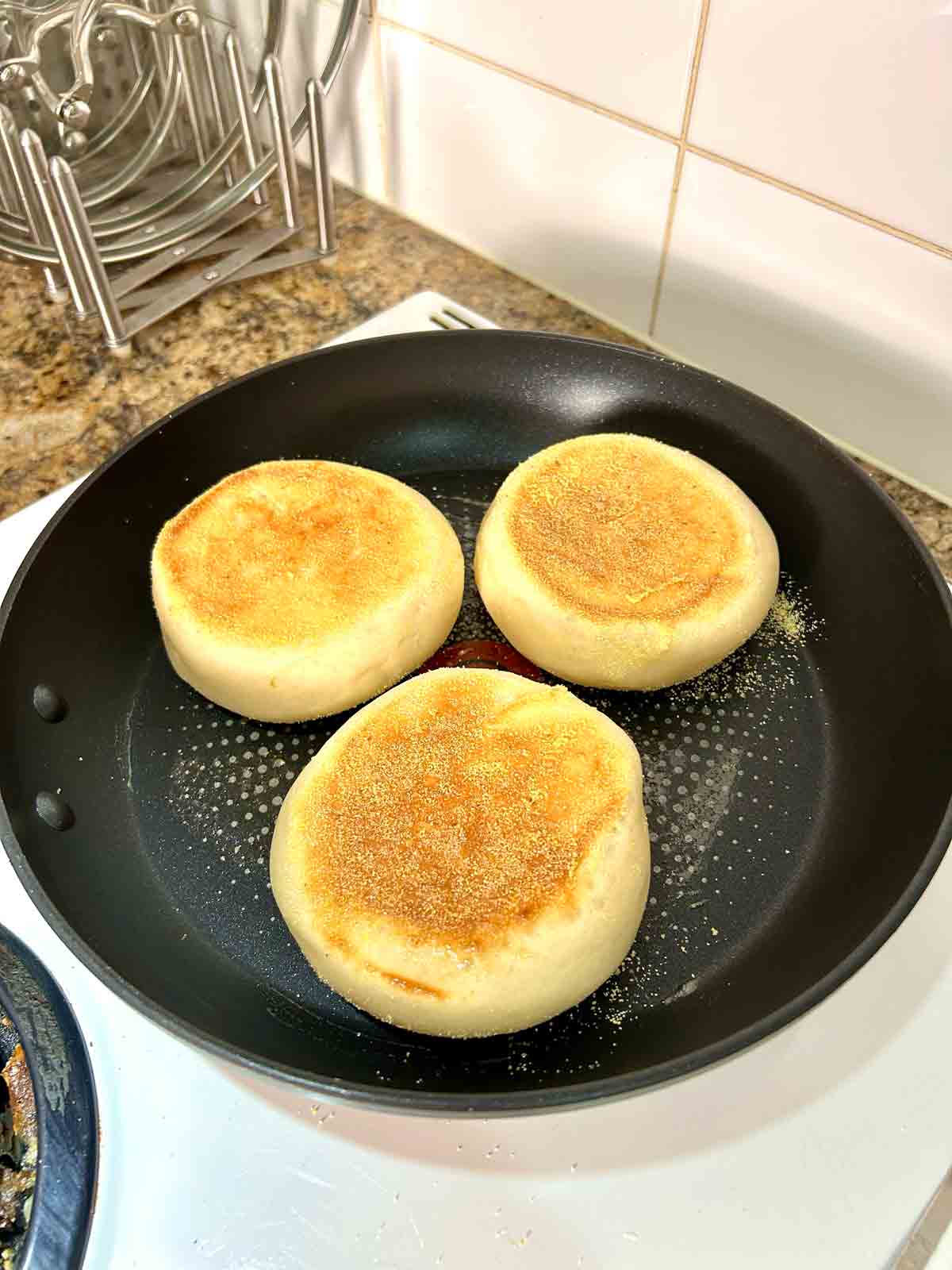 second side of English muffin being cooked in skillet.
