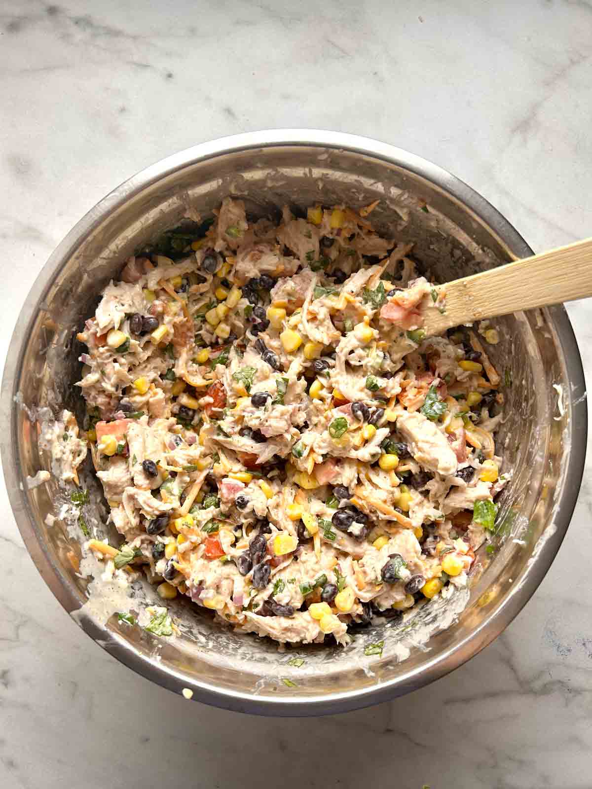 chicken, vegetables, and dressing tossed together in bowl.