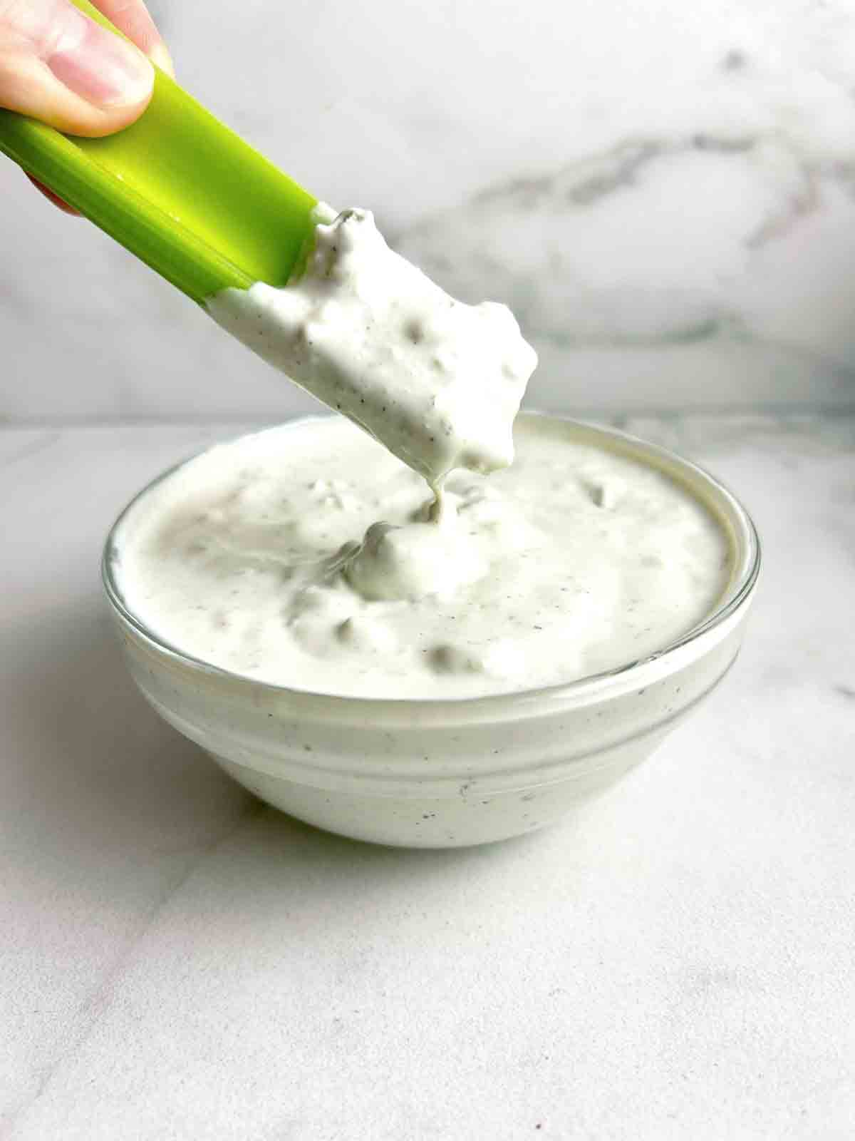 celery dipped into bowl of dressing.