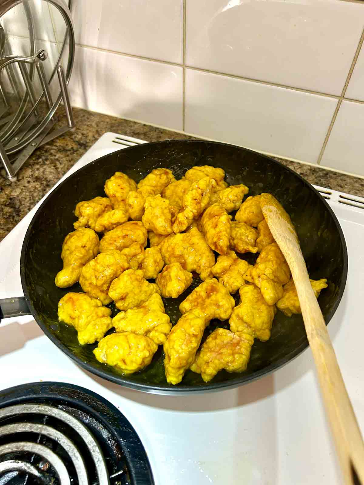 fried chicken tossed with lemon sauce in skillet.
