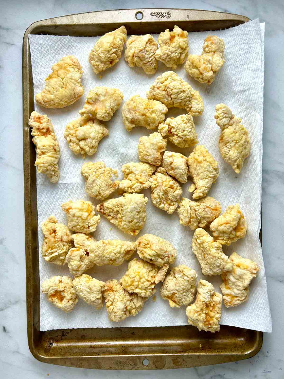 fried chicken pieces draining on paper towels.