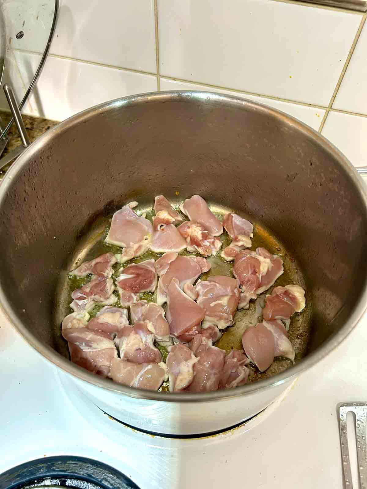 chicken thighs being seared in pot.