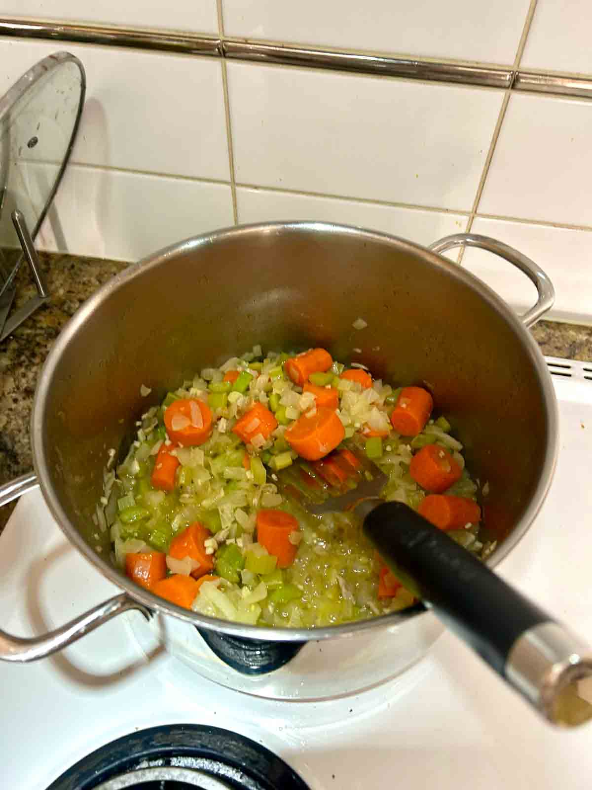 vegetables being sautéed in pot.
