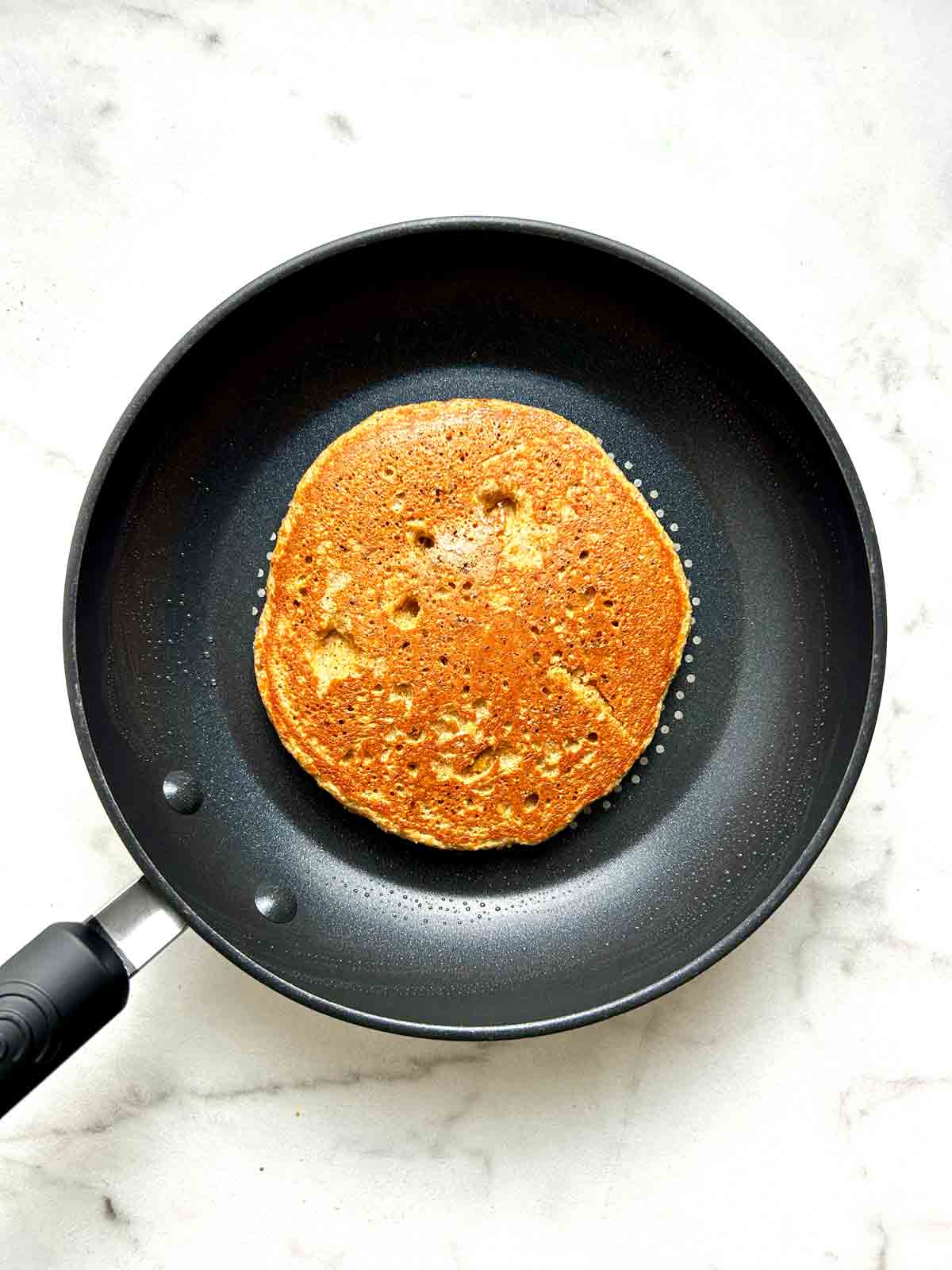 second side of pancake being cooked in pan.