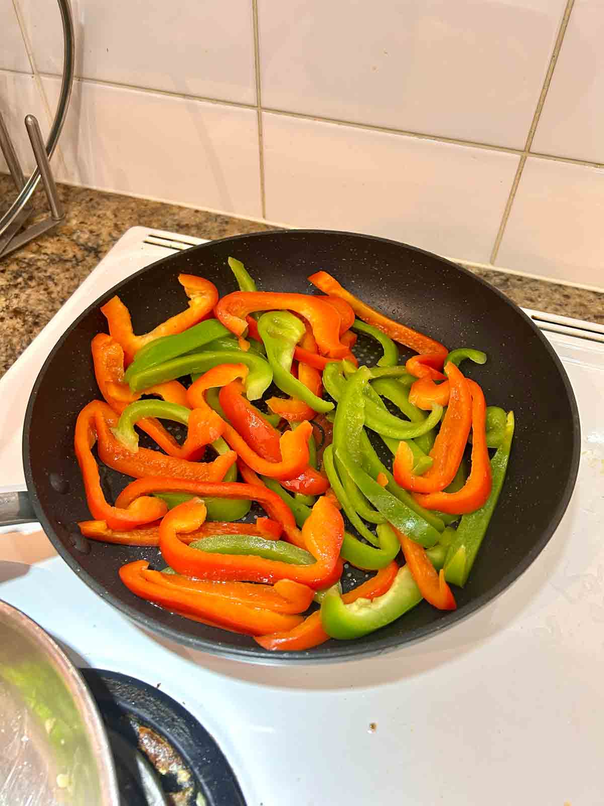 bell peppers being sautéed in pan.