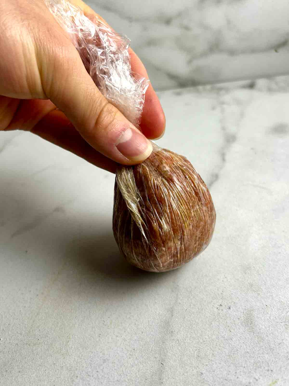 egg with meat wrapped around it using plastic wrap.