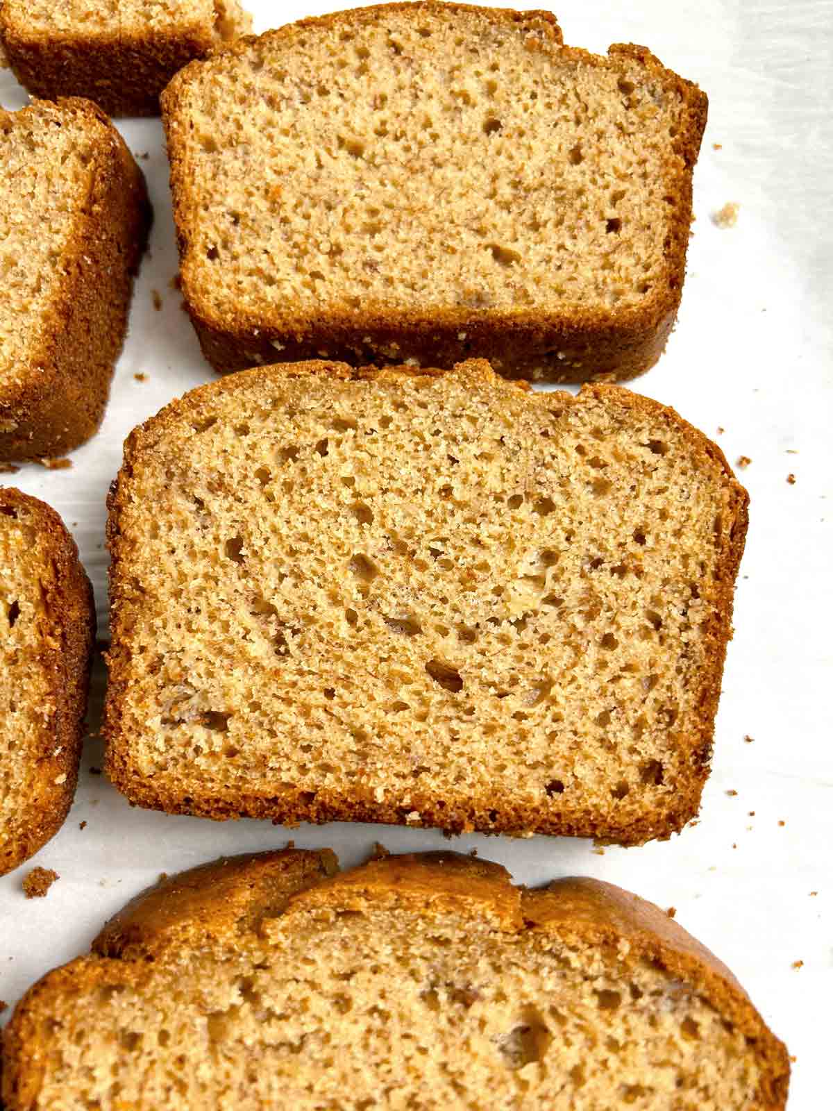 close up of slices of banana bread on parchment paper.