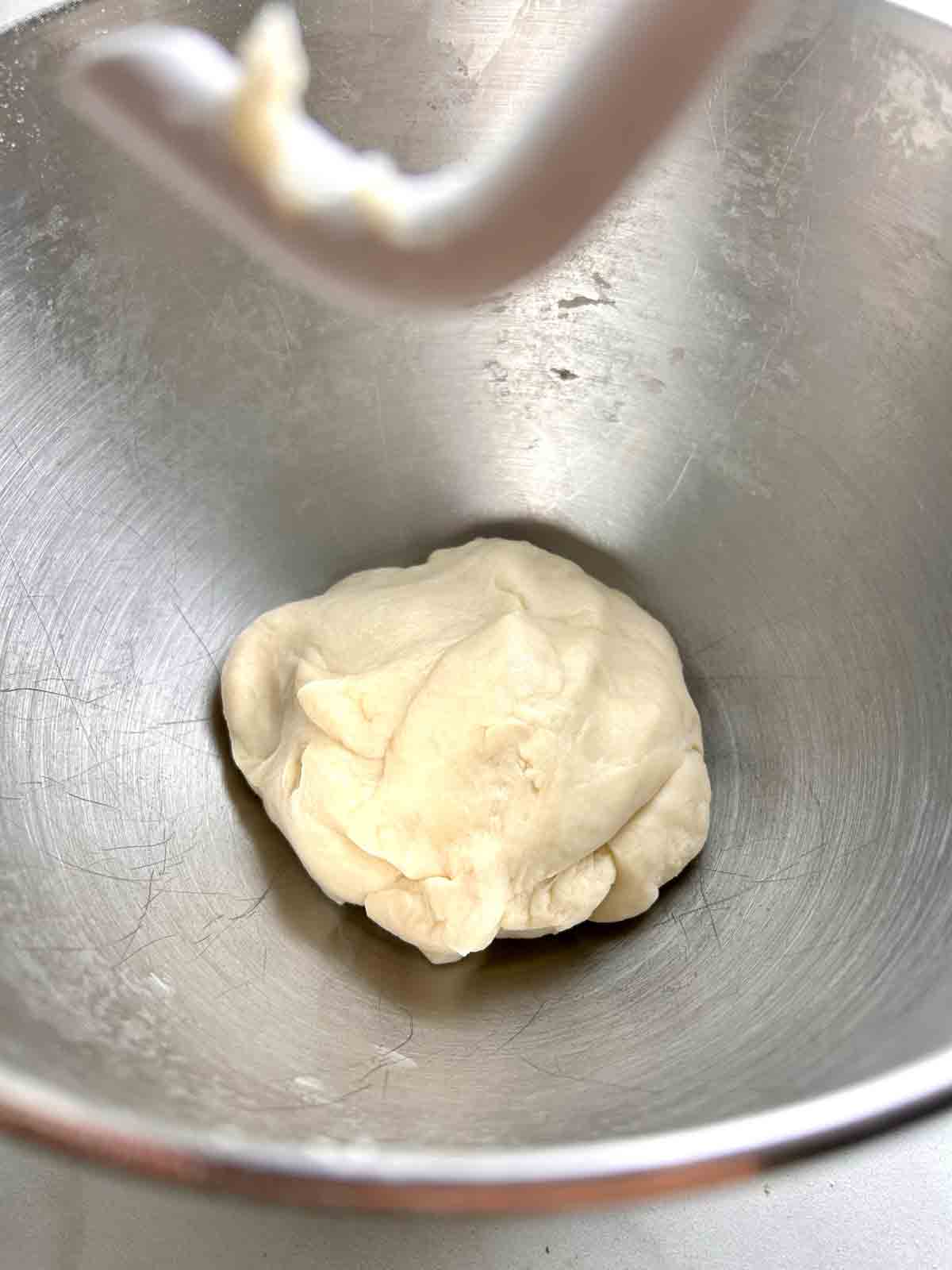 dough kneaded in stand mixer bowl.