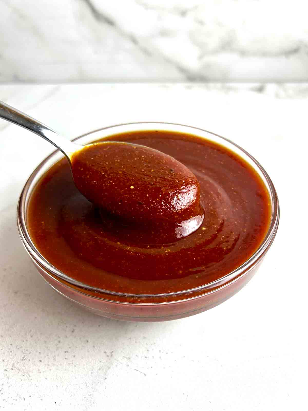 spoon lifting barbecue sauce from bowl.