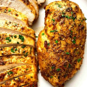 close up of air-fried chicken breasts on plate; one is sliced.