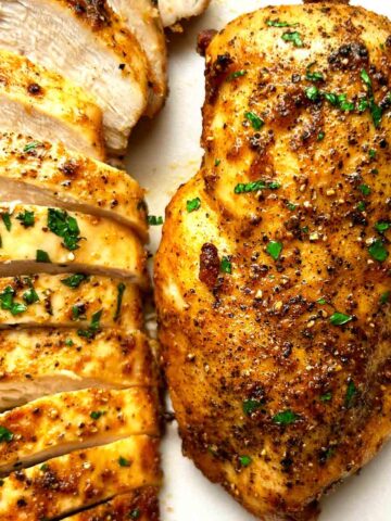 close up of air-fried chicken breasts on plate; one is sliced.
